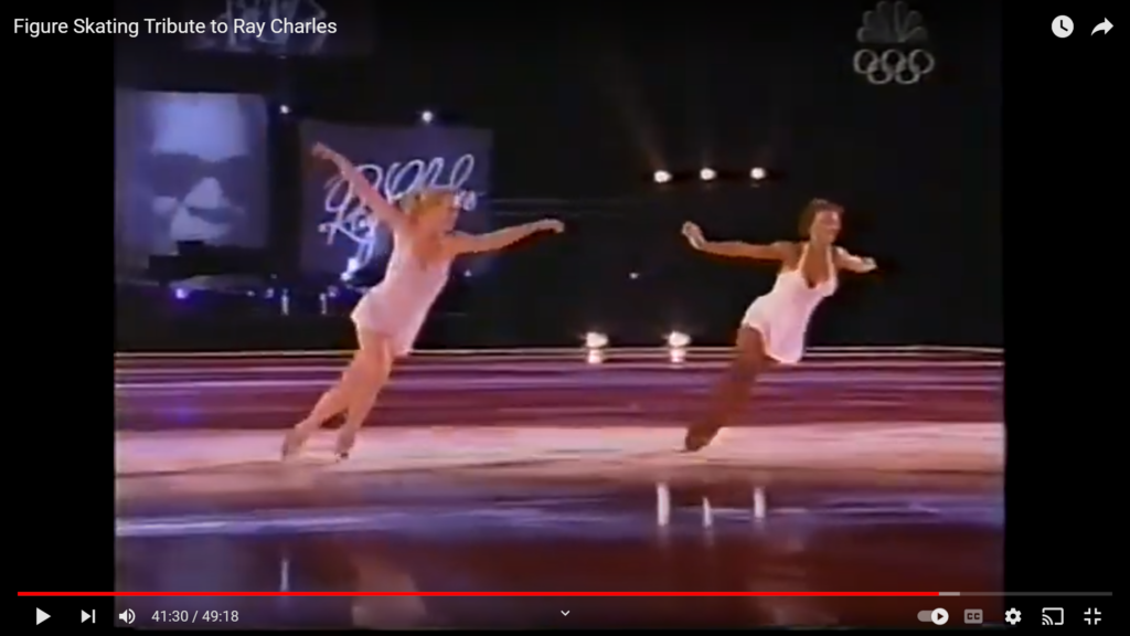 Still image from television special of figure skaters tributing Ray Charles on ice includes this one black skater in a mostly white ensemble of ice dancers